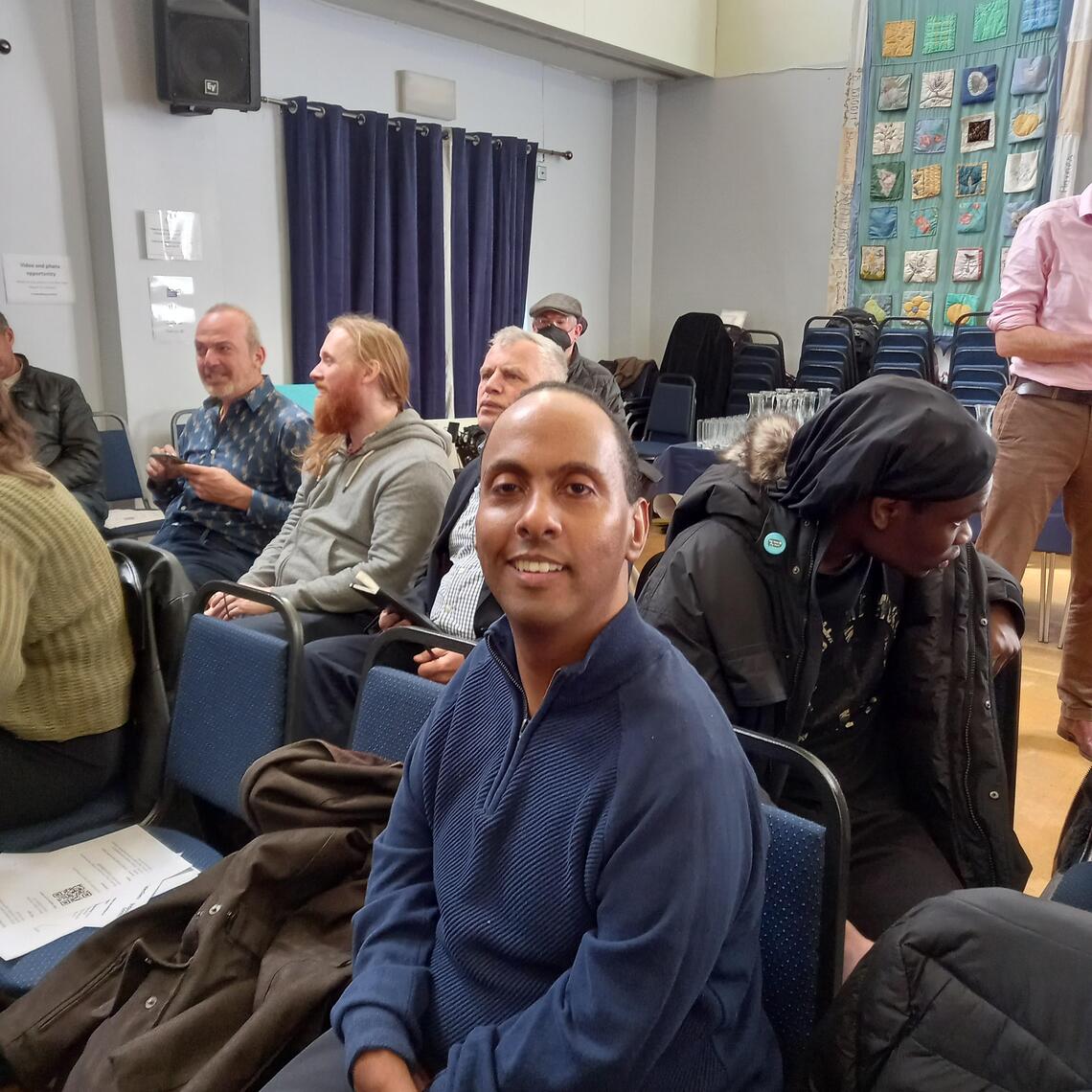 Vice Chair Estifanos sat smiling at IL hustings 